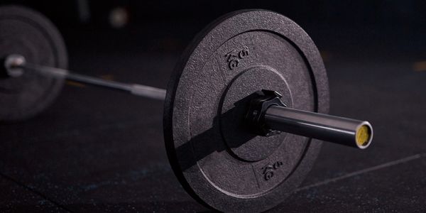 Close-up of a barbell with weight plates on a gym floor.