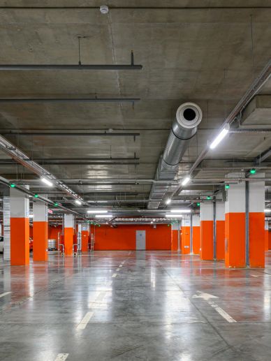 Interior of an automated parking garage with orange support columns and rows of parked cars