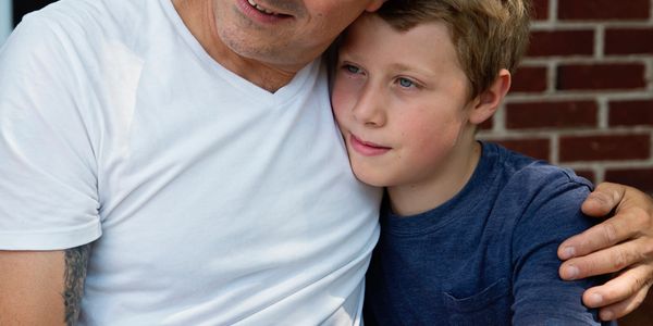 Father and son share a warm, comforting embrace outdoors.