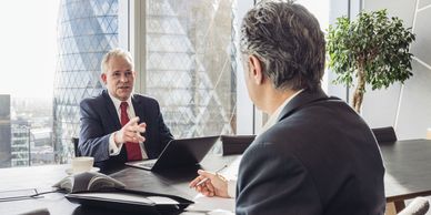 Two businessmen having a discussion in a modern office with city views.