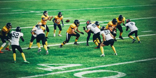 Football game with players in yellow and white uniforms.
