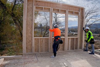 Modern tiny house with black metal siding and wooden porch under construction.