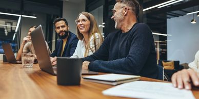 Colleagues smiling and collaborating in a modern office meeting.