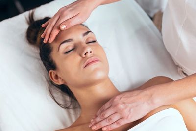 Reiki practitioner using reiki energy healing on woman