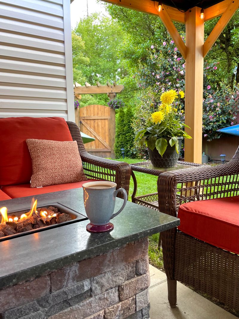 Backyard patio with coffee by the fireplace, green grass and wicker chairs