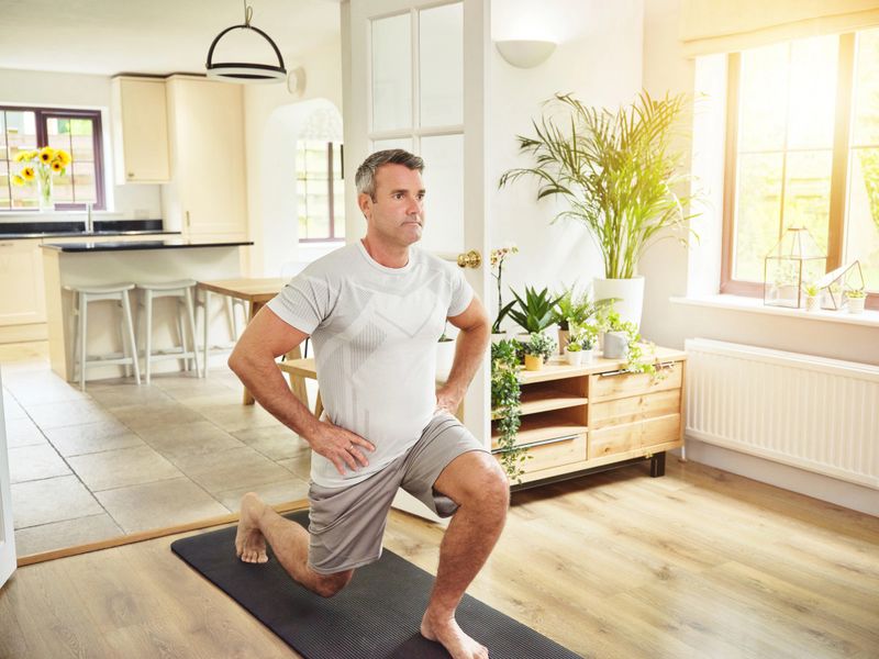 Personal trainer performing posture and strength assessment with senior client at home