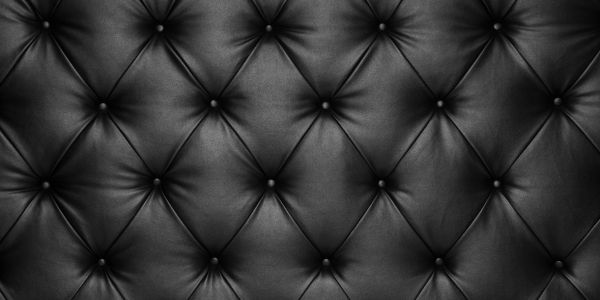 Close-up of black tufted leather upholstery with button details.