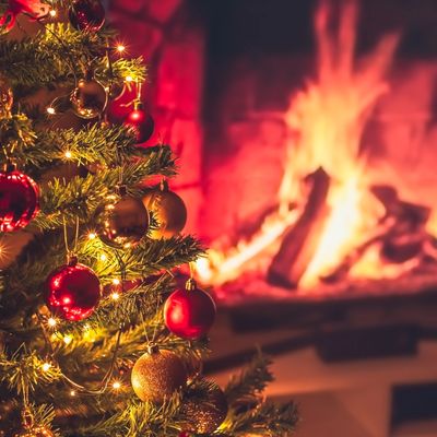 Christmas tree with ornaments near a cozy fireplace.