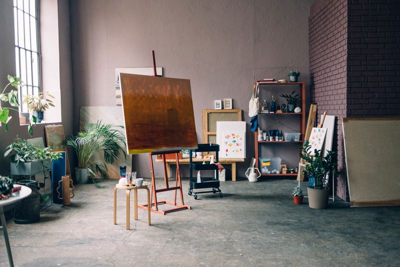 A wide angle shot of a painting on an easel in an art studio.