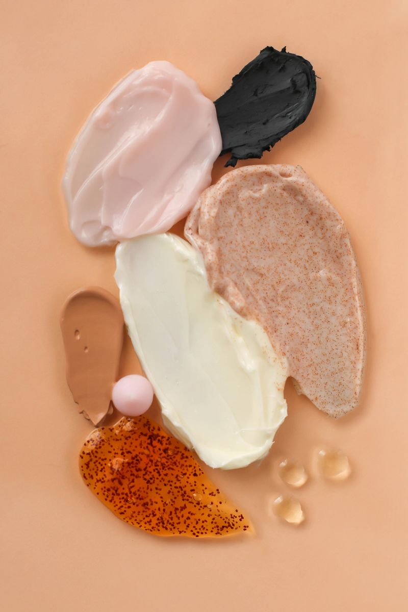 Cosmetic smears of creams, scrub and cosmetic oils on a beige background close-up. Stylish concept of organic creams and essences, beauty and health products. Flat lay. Body and skin care, hydration