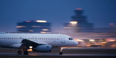 Airplane taking off at night with blurred city lights.