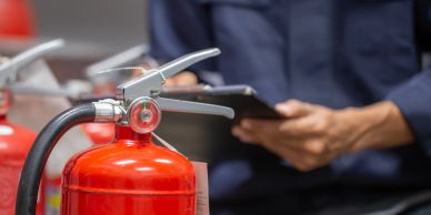 Close-up of fire extinguishers with person checking clipboard.