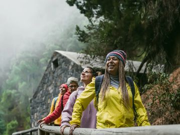 Group of friends enjoying a misty outdoor hike by a stone building.