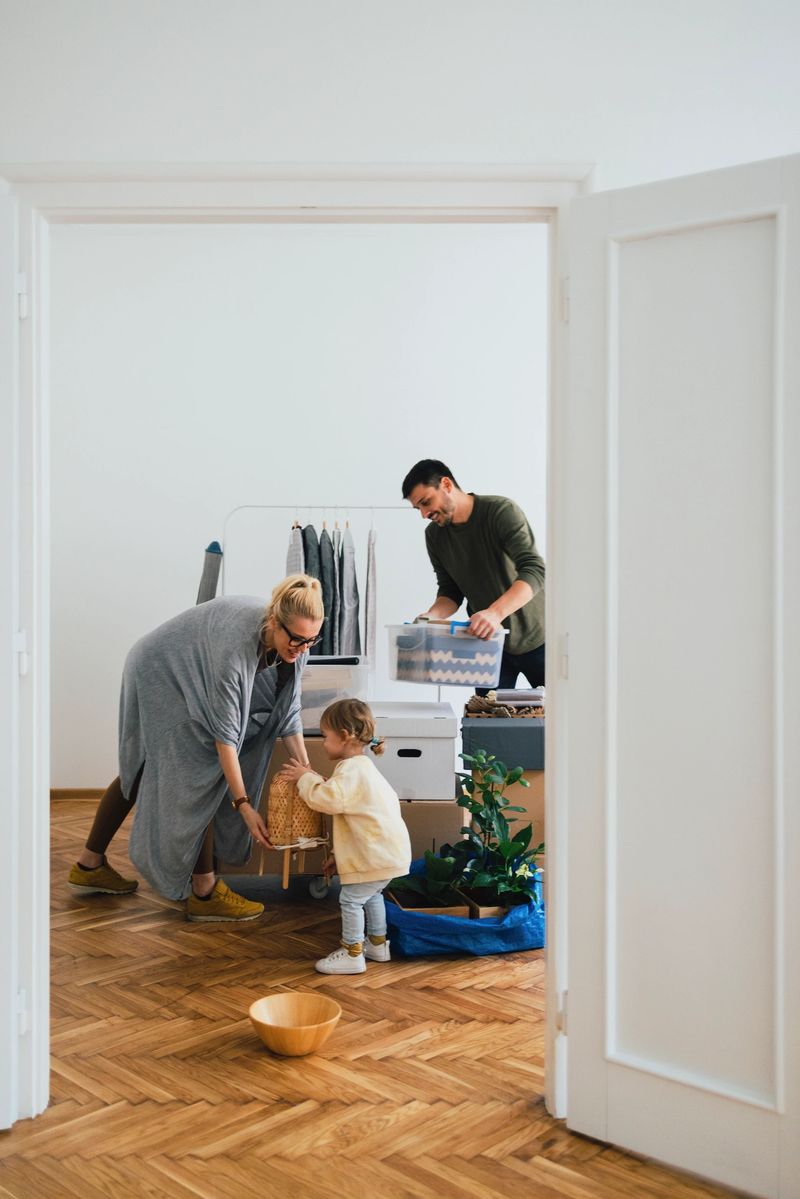 Happy family with one child unpacking boxes together in new home on moving day.
