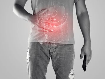 Man holding stomach with digestive system overlay and red pain highlight.