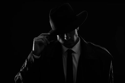 Man in suit and hat in low light.