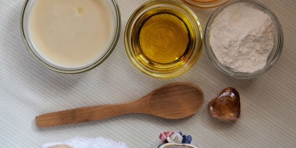 Ingredients including flour, oil, and milk with a wooden spoon.