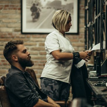 A barber and a client in a rustic barbershop setting.