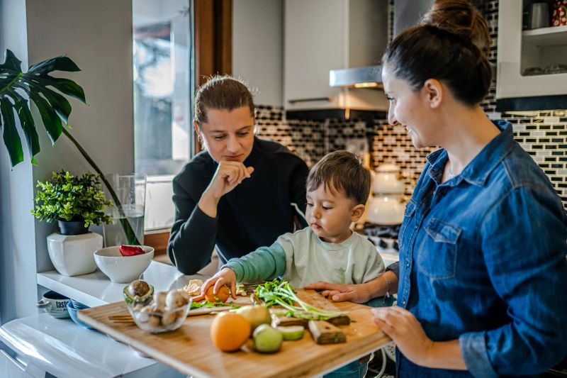 Same sex couple and their child preparing dinner in kitchen