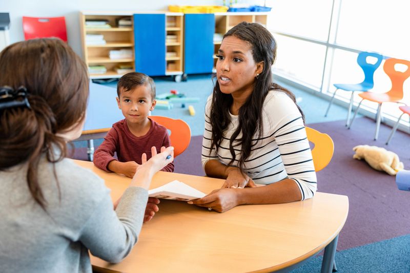 An attentive mother listens as her son's teacher discusses his progress during a parent teacher conference.