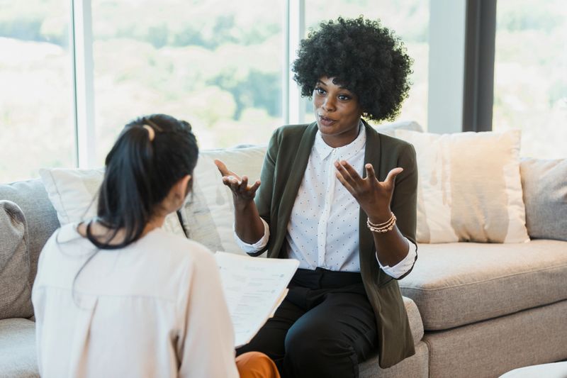 A mid adult female job applicant gestures as she discusses her qualifications with a potential employer.