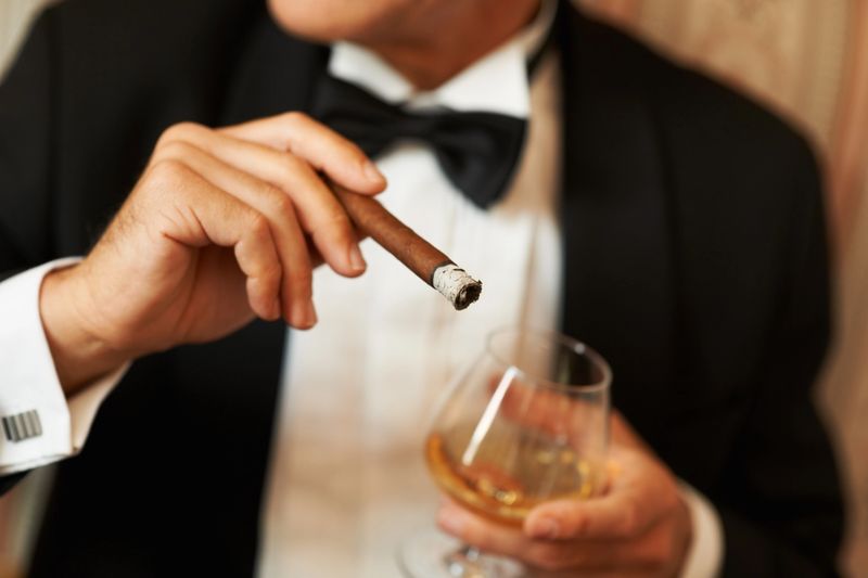 Closeup of a wealthy man in a tuxedo holding a cigar and glass of brandy