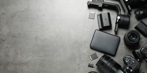 Photography gear including camera, lenses, memory cards, and accessories on a gray surface.