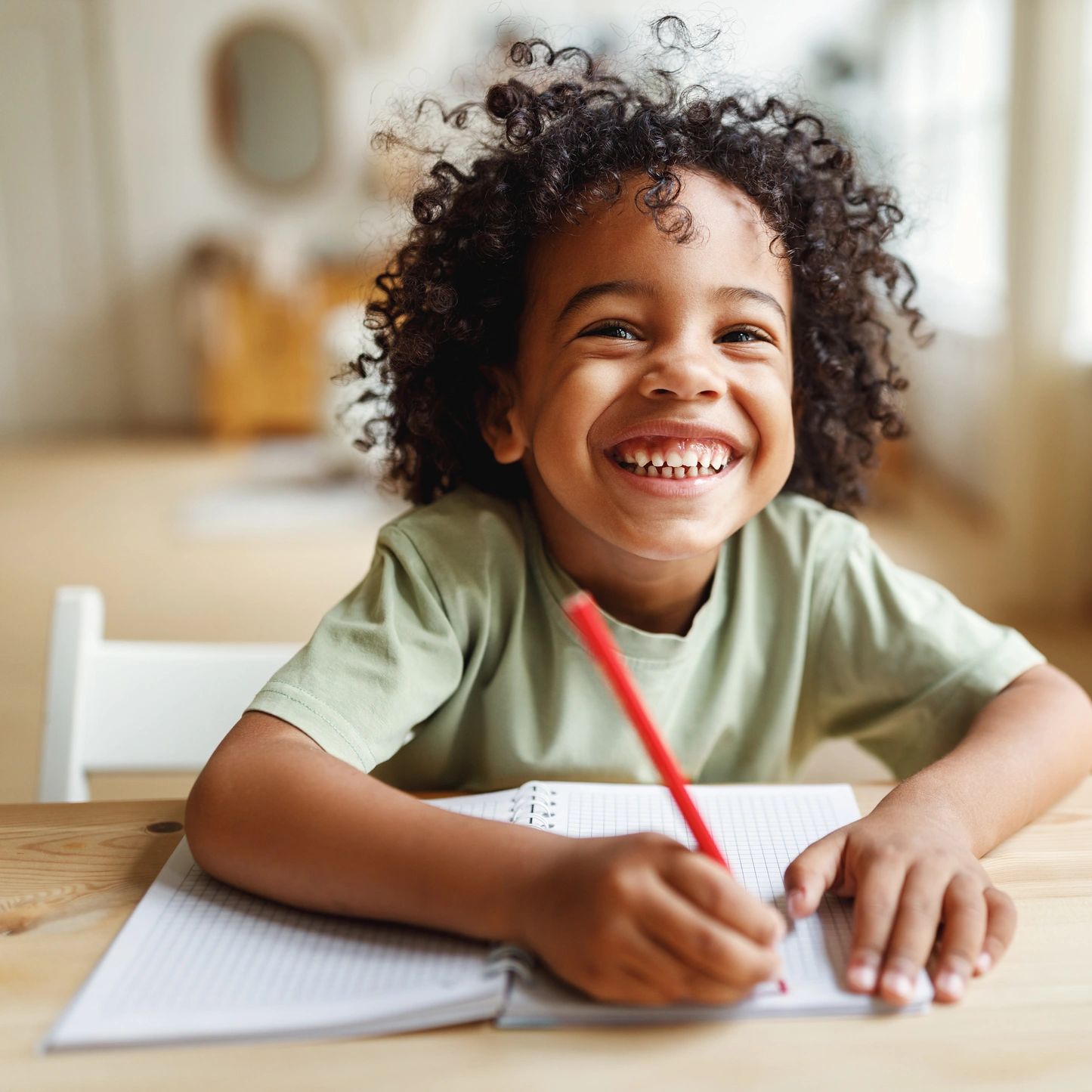 Smiling child focused on writing at a table