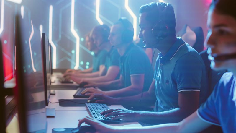 Diverse Esport Team of Pro Gamers Playing in Video Game on World Championship, use Headsets to Talk. Stylish Neon Cyber Games Arena. Online Broadcasting of Tournament Event