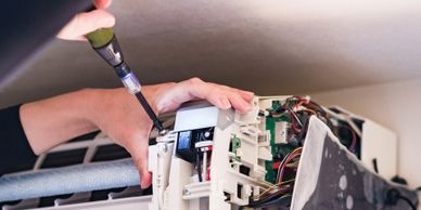 Person repairing an air conditioning unit using a screwdriver.