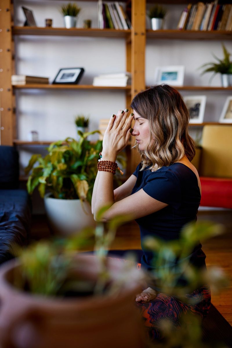 A spiritual yogi woman sitting at home on a yoga mat in a lotus pose and praying. Yogi woman practicing yoga at home.