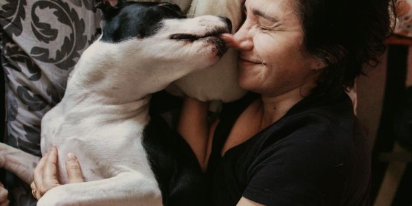 Dog affectionately licking a woman's nose.