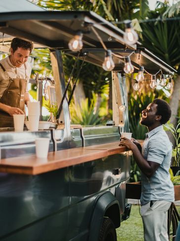 Customer smiling and ordering drink at an outdoor coffee truck.