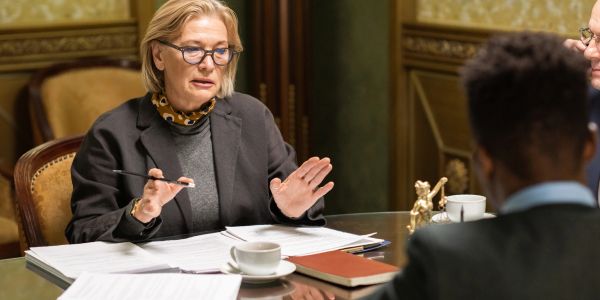 Mulher discutindo documentos em uma reunião formal.