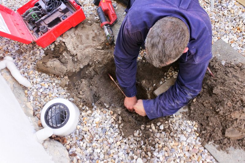 Aerial view of an Australian plumber fixing an underground hot water pipe leaking with a tools.