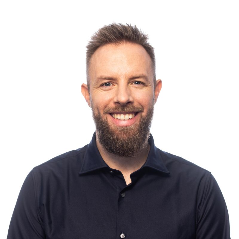 Smiling young man with a beard looking at the camera during a studio portrait session in front of white background