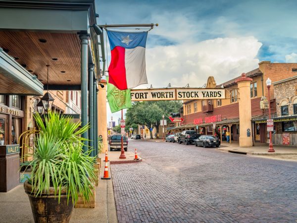 Fort Worth Stock Yards entrance with Texas flag and street view.