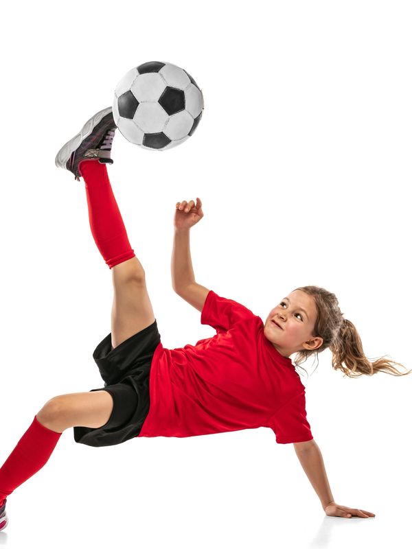 Young girl performing an impressive soccer kick mid-air.