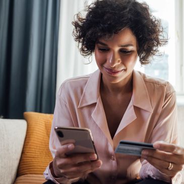 Woman holding credit card and phone.