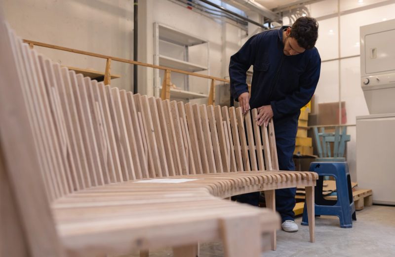 Latin American carpenter sanding a wood bench at the workshop - carpentry concepts