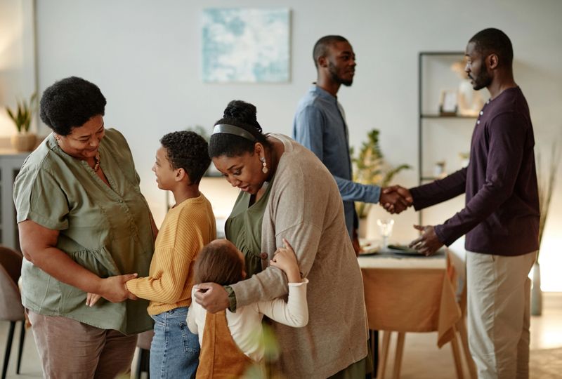Portrait of big African-American family chatting while welcoming guests for dinner party at home