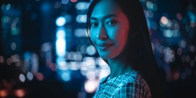Portrait of a woman illuminated by blue and red city lights at night.