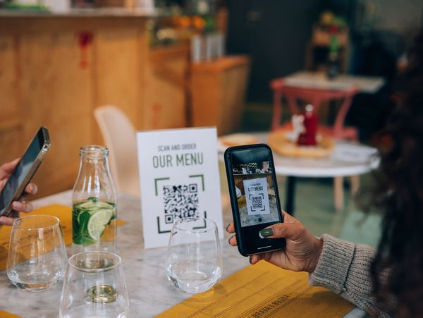 People scanning a QR code to view a menu at a restaurant table.