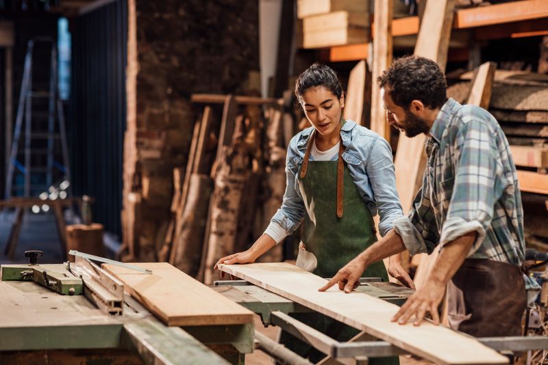 Carpenter and his apprentice working with sustainable locally sourced wood in a workshop in the North East of England. They are making handcrafted furniture and they are a family business.
