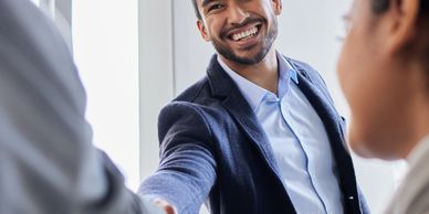 Businessman smiling while shaking hands with colleagues in office.