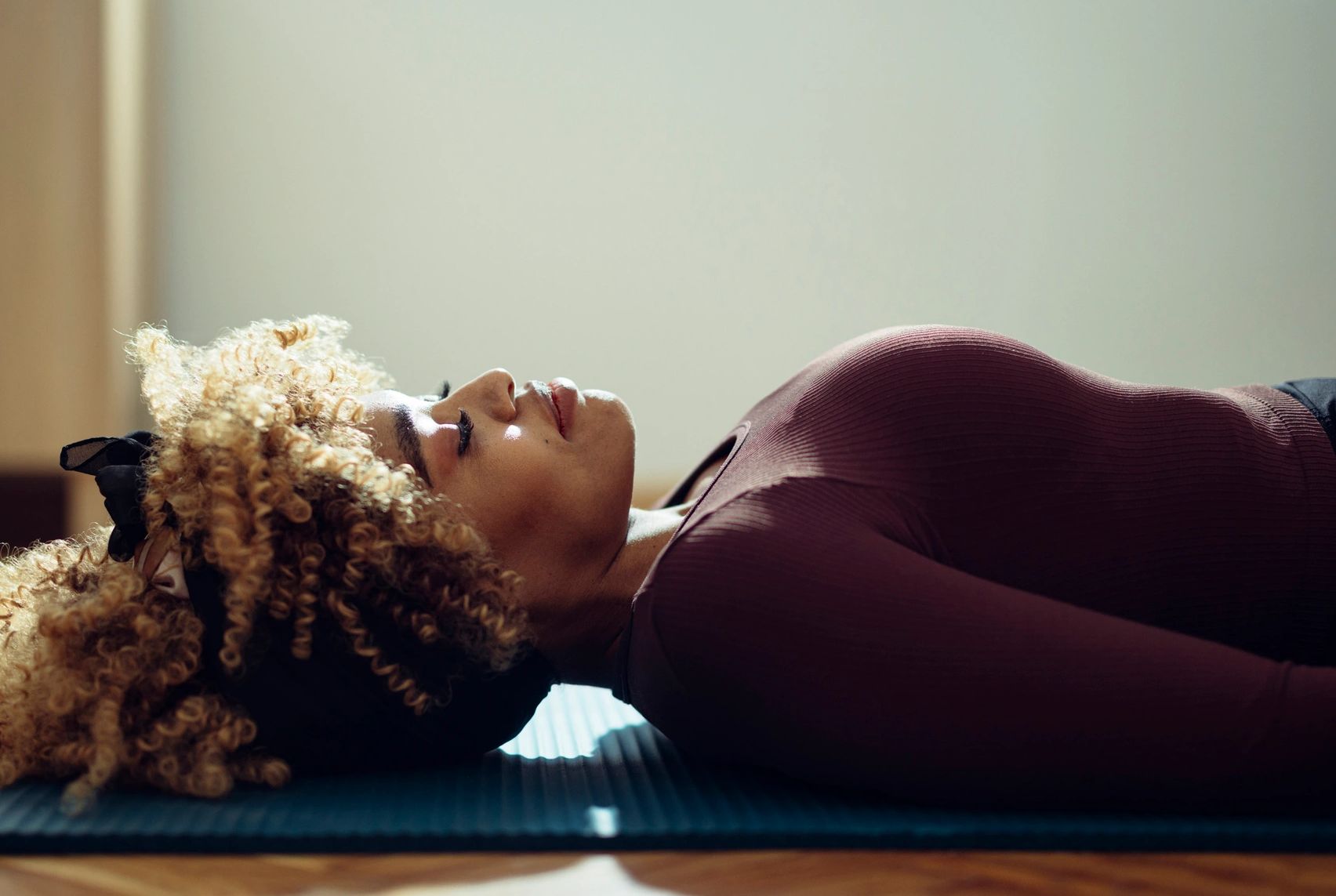 Woman lying on a yoga mat with eyes closed.