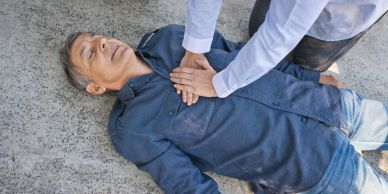 Person performing CPR on a man lying on the ground.