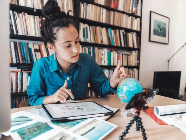 Young person studying geography with a globe and tablet.