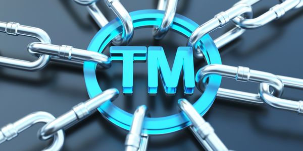 Blue TM symbol linked by silver chains representing trademark protection.