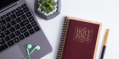 Bible, laptop, and stationery on desk.
